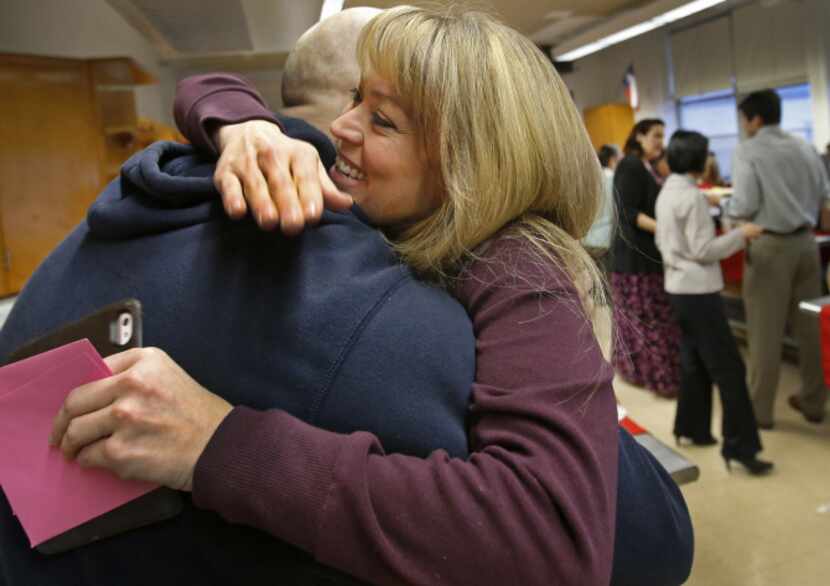 Thomas Jefferson High School principal Sandi Massey hugs pastor Adam Griffin as members of...