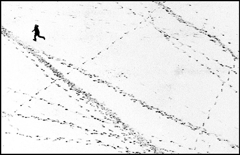  March 20, 1984--As seen from a helicopter, a child runs along a snow-covered vacant field...