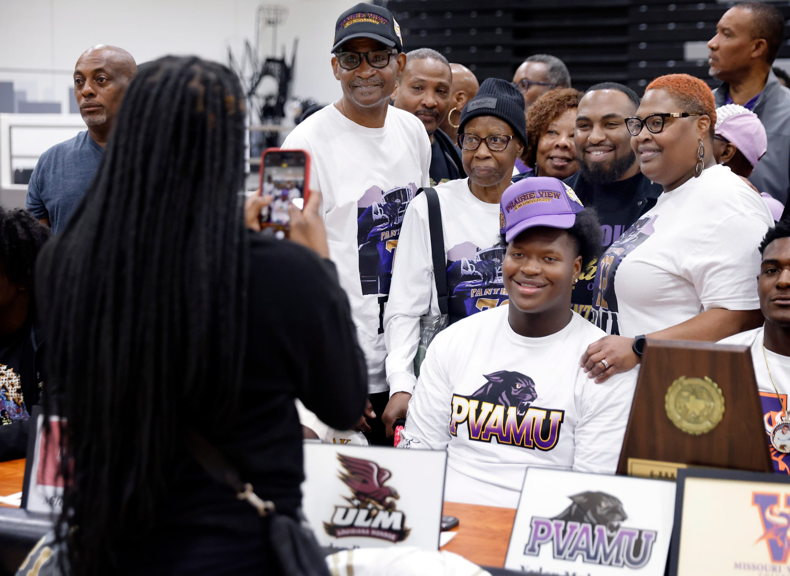 South Oak Cliff football player Xyler Myles (seated, center) has his photo taken with...