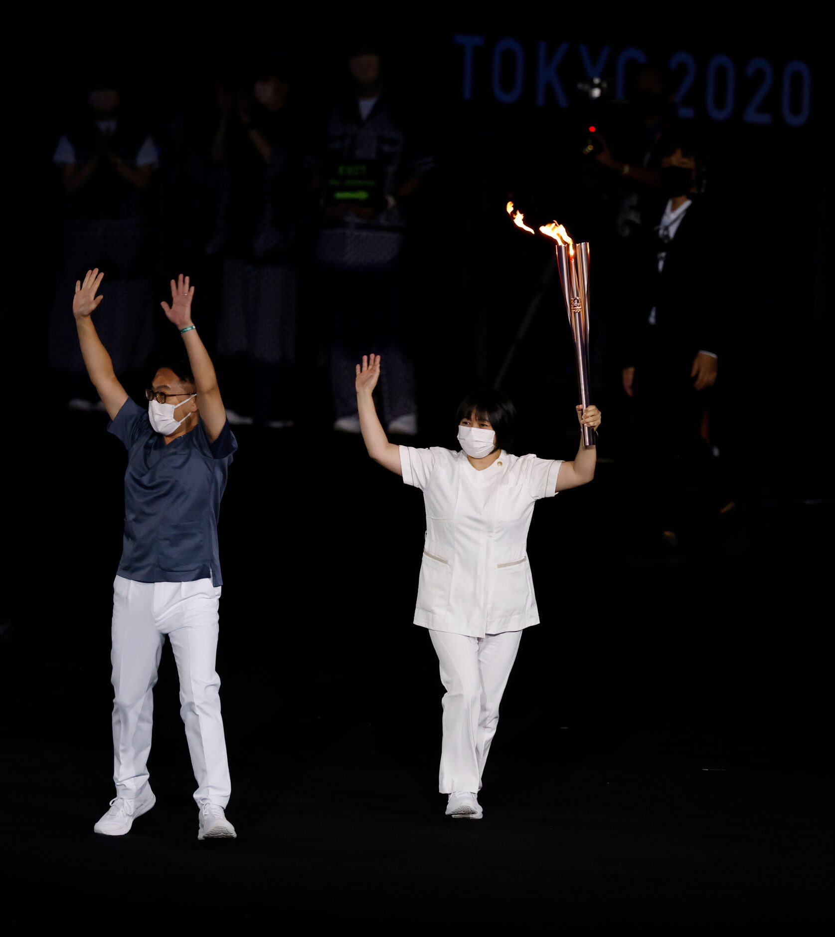 Hiroki Oohashi, doctor and Junko Kitagawa, nurse carry the Olympic flame during the opening...