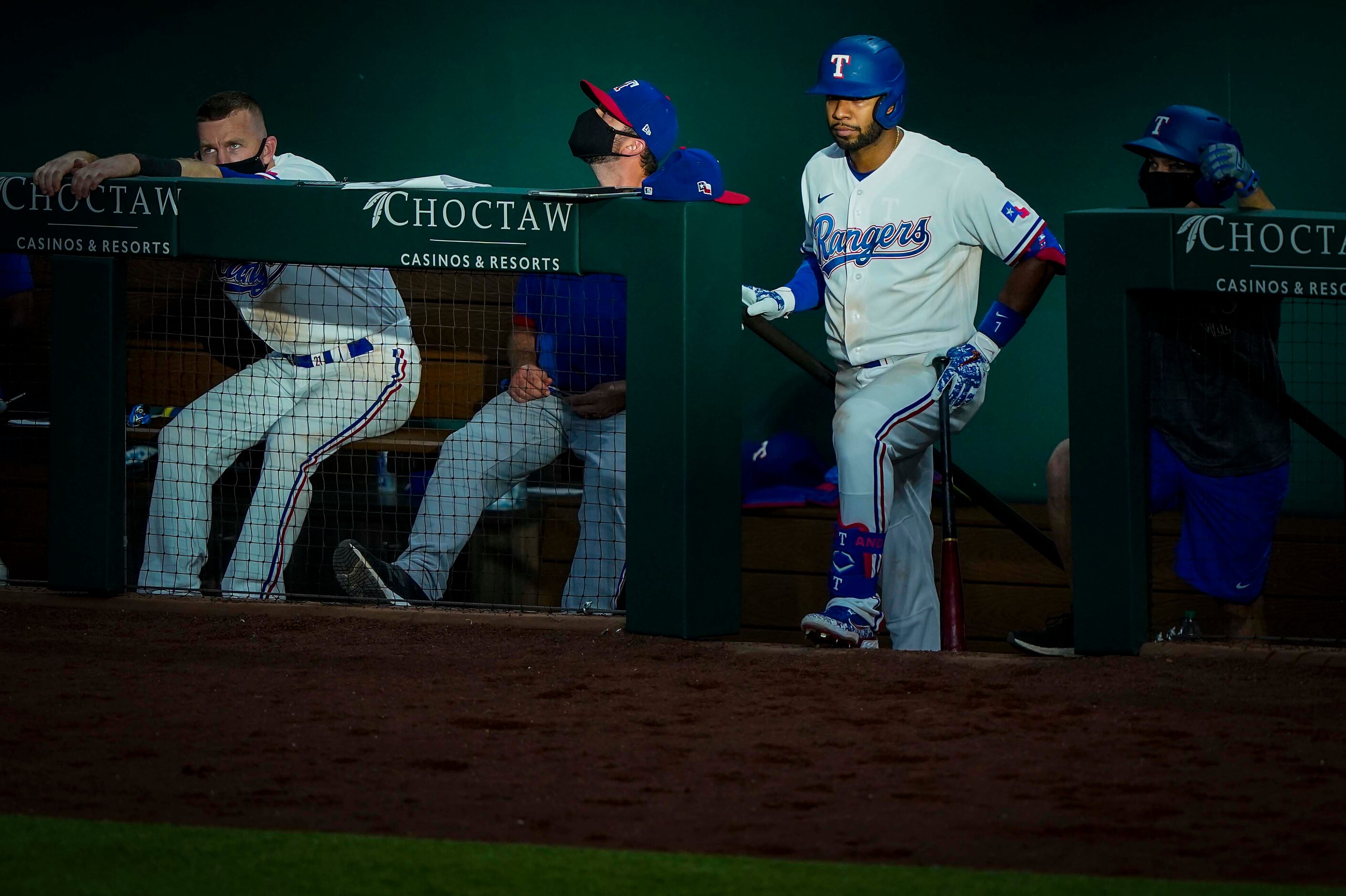 Shortstop Elvis Andrus looks out from the top of the dugout steps as evening sunlight...