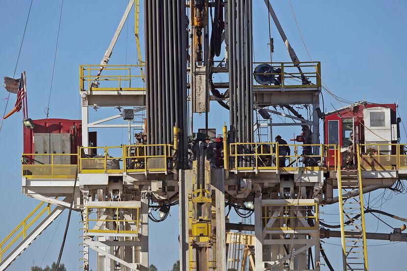 File photo of of workers standing on the platform of a fracking rig in the Permian Basin oil...