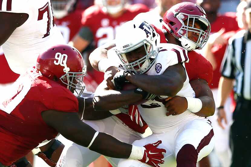 Tra Carson #21 of the Texas A&M Aggies is tackled by Jarran Reed #90 and Ryan Anderson #7 of...