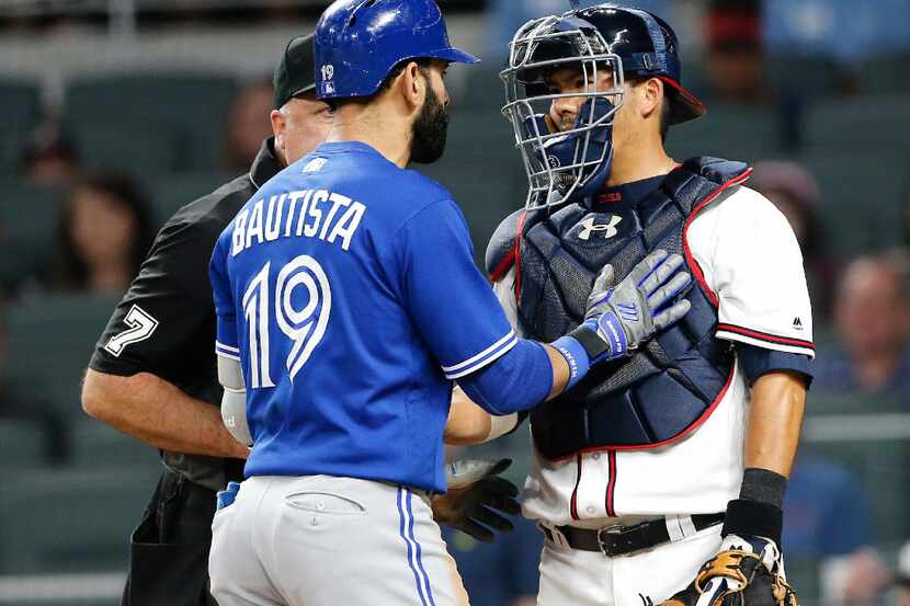 Toronto Blue Jays' Jose Bautista (19) exchanges words with Atlanta Braves catcher Kurt...