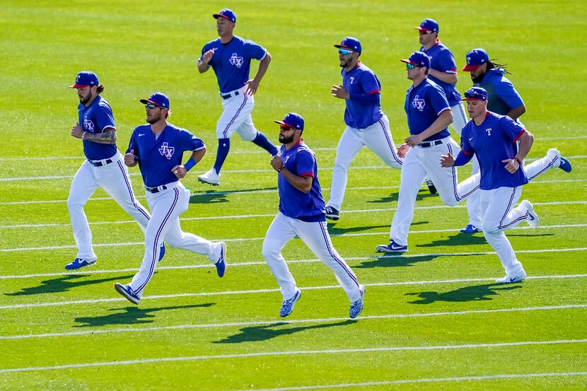 Texas Rangers position players run on a practice field during a spring training workout at...