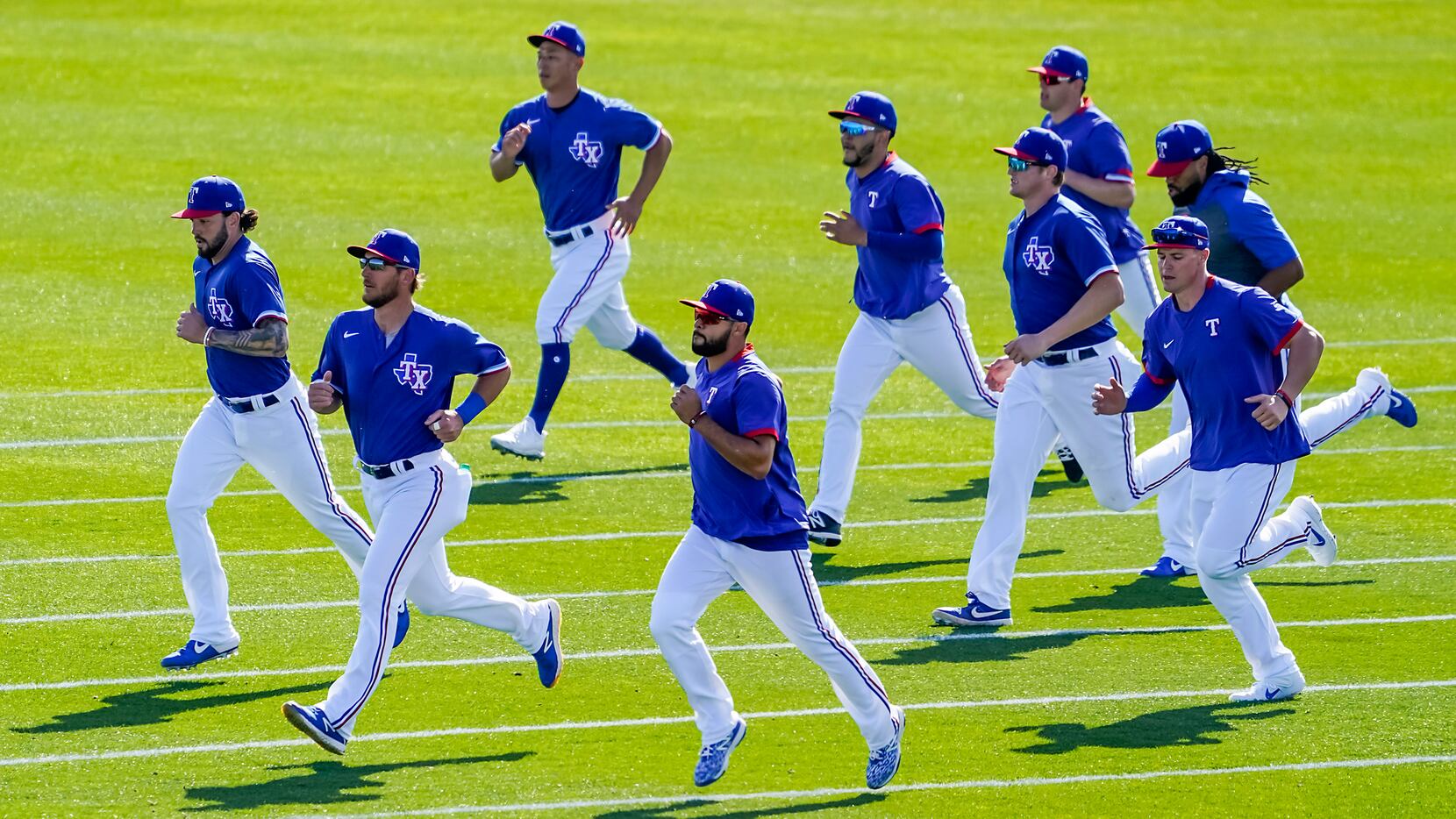 Texas Rangers position players run on a practice field during a spring training workout at...