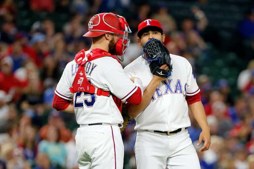 Texas Rangers catcher Jonathan Lucroy (25) talks with starting pitcher Martin Perez, right,...