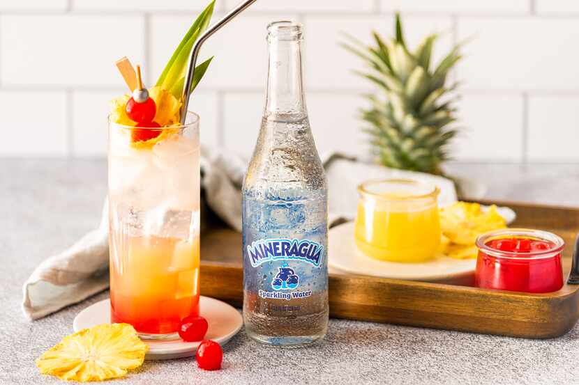 A bottle of Mineragua is used to create an aguas frescas recipe, including pineapples,...