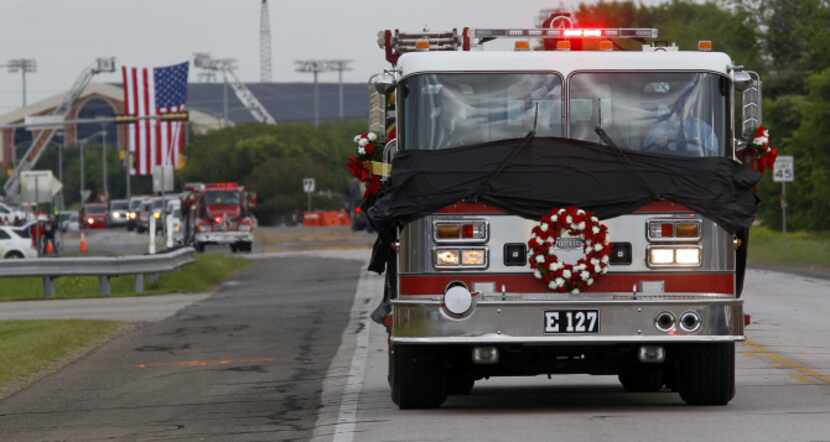 An Abbott, Texas, fire truck hung with black cloth and a wreath rolls out with a procession...