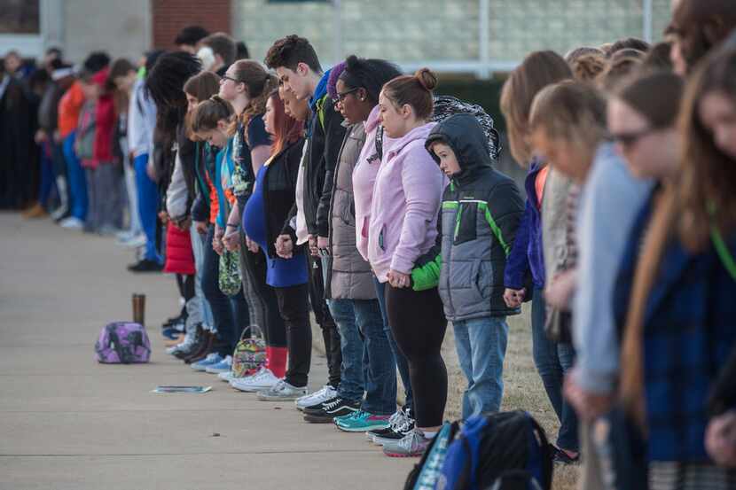 Students and community members hold hands in prayer before classes at Paducah Tilghman High...