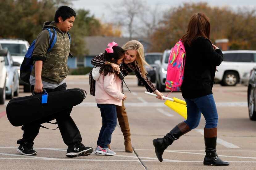 Second-grader Carla Puente, 7, gets a hug from principal Aimee Lewis at McKenzie Elementary...