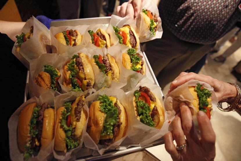 People grab cheeseburgers during the house warming party for Shake Shack in Dallas, TX Aug....