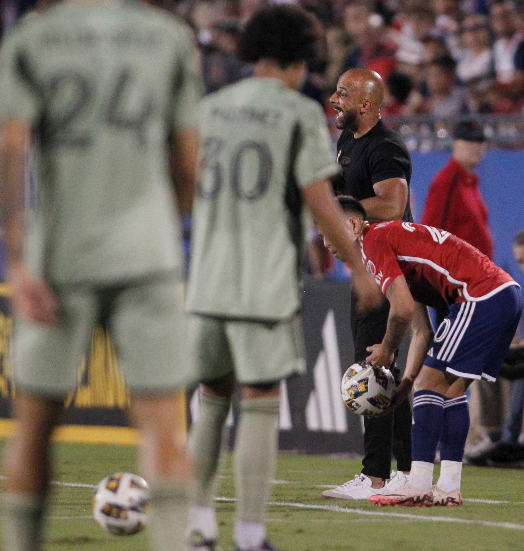 FC Dallas head coach Peter Luccin, right, sends game strategy to his players from the team...