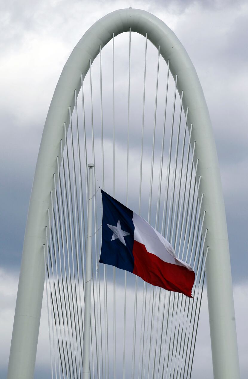 The Texas flag flutters near the Margaret Hunt Hill Bridge.