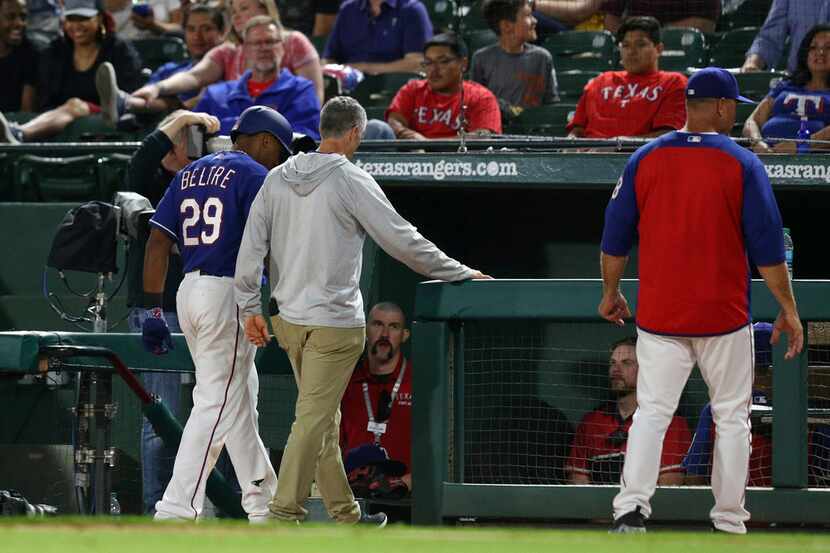 Texas Rangers' Adrian Beltre walks off the field with athletic trainer Kevin Harmon, center,...