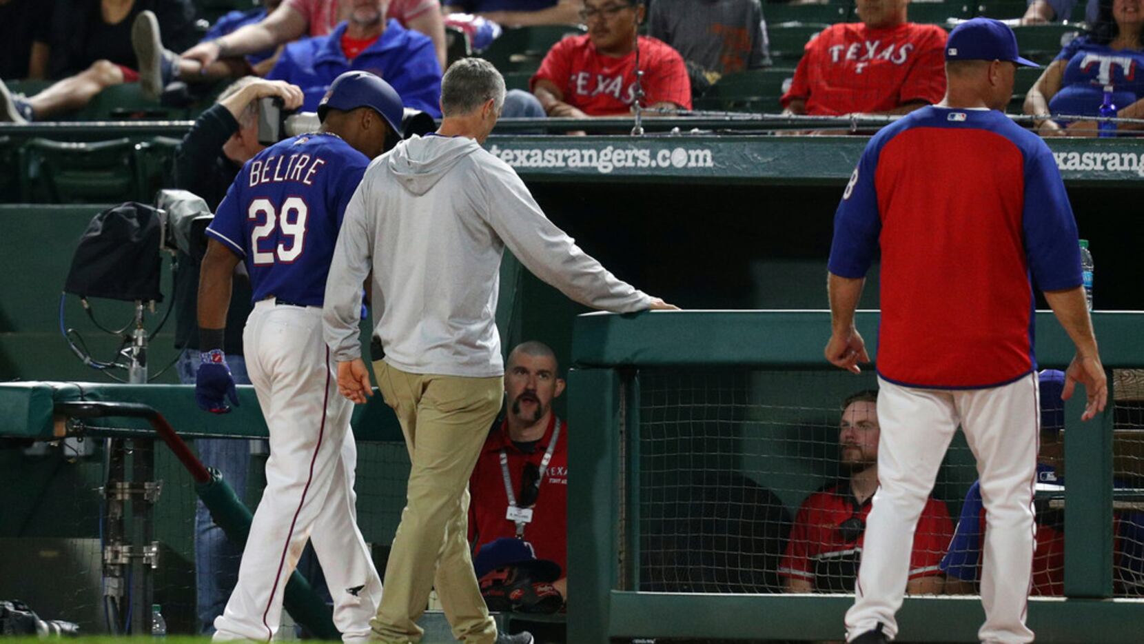 Texas Rangers' Adrian Beltre walks off the field with athletic trainer Kevin Harmon, center,...