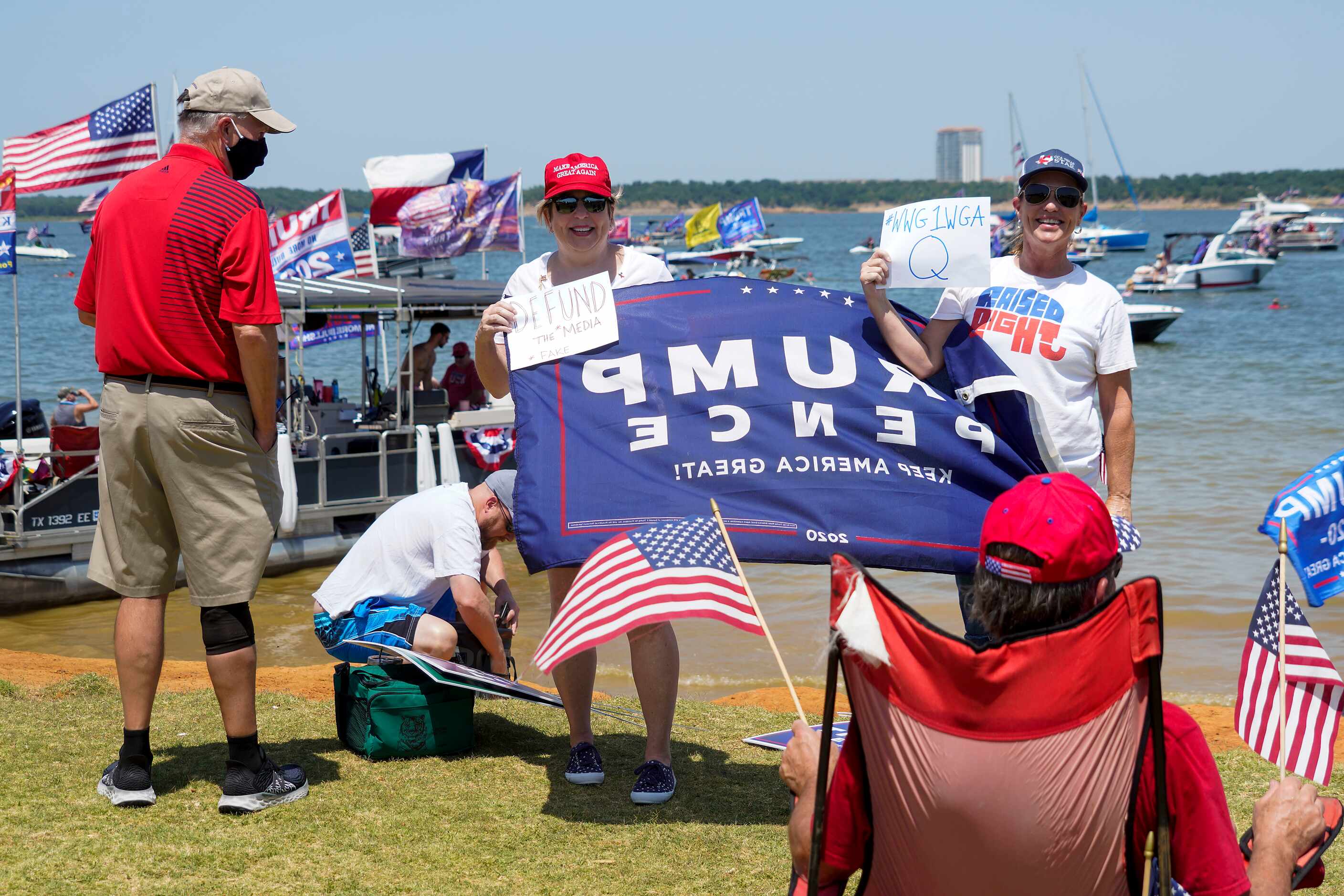 Supporters of President Donald Trump pose for photos holding signs in support of QAnon, and...