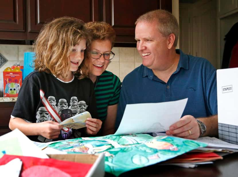 Katie Harris,  8, and her parents, Jennifer and Skip Harris, sort through schoolwork from...