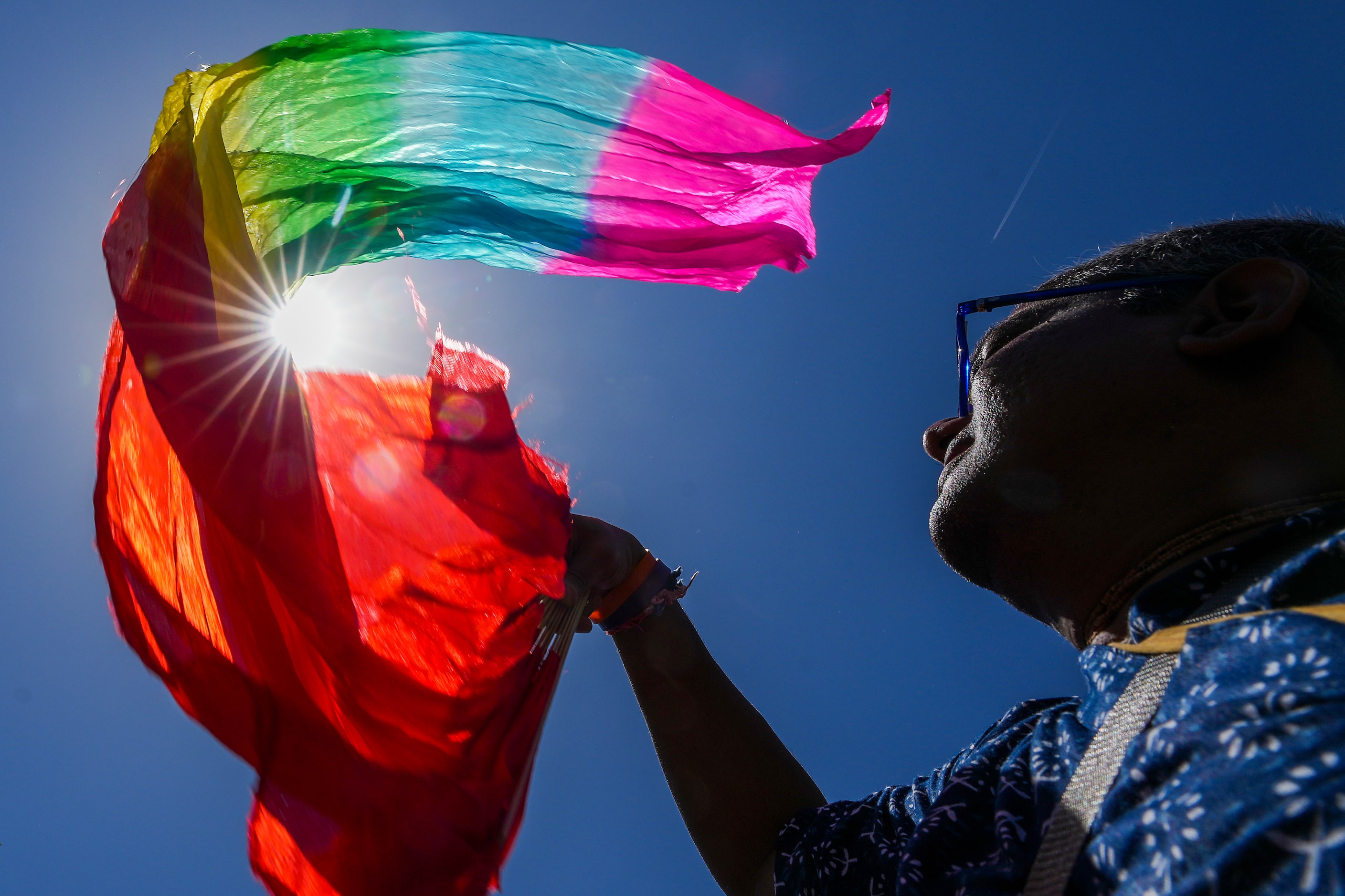 Sri Giriraj Das waves a colored dance fan against the clear blue skies over Klyde Warren...