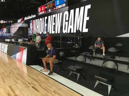 Plexiglass protects the scorers table and the chairs in the team bench areas are spread a...