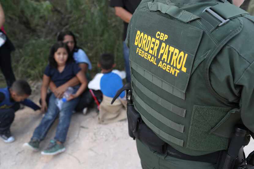 Central American asylum seekers wait as U.S. Border Patrol agents take them into custody on...