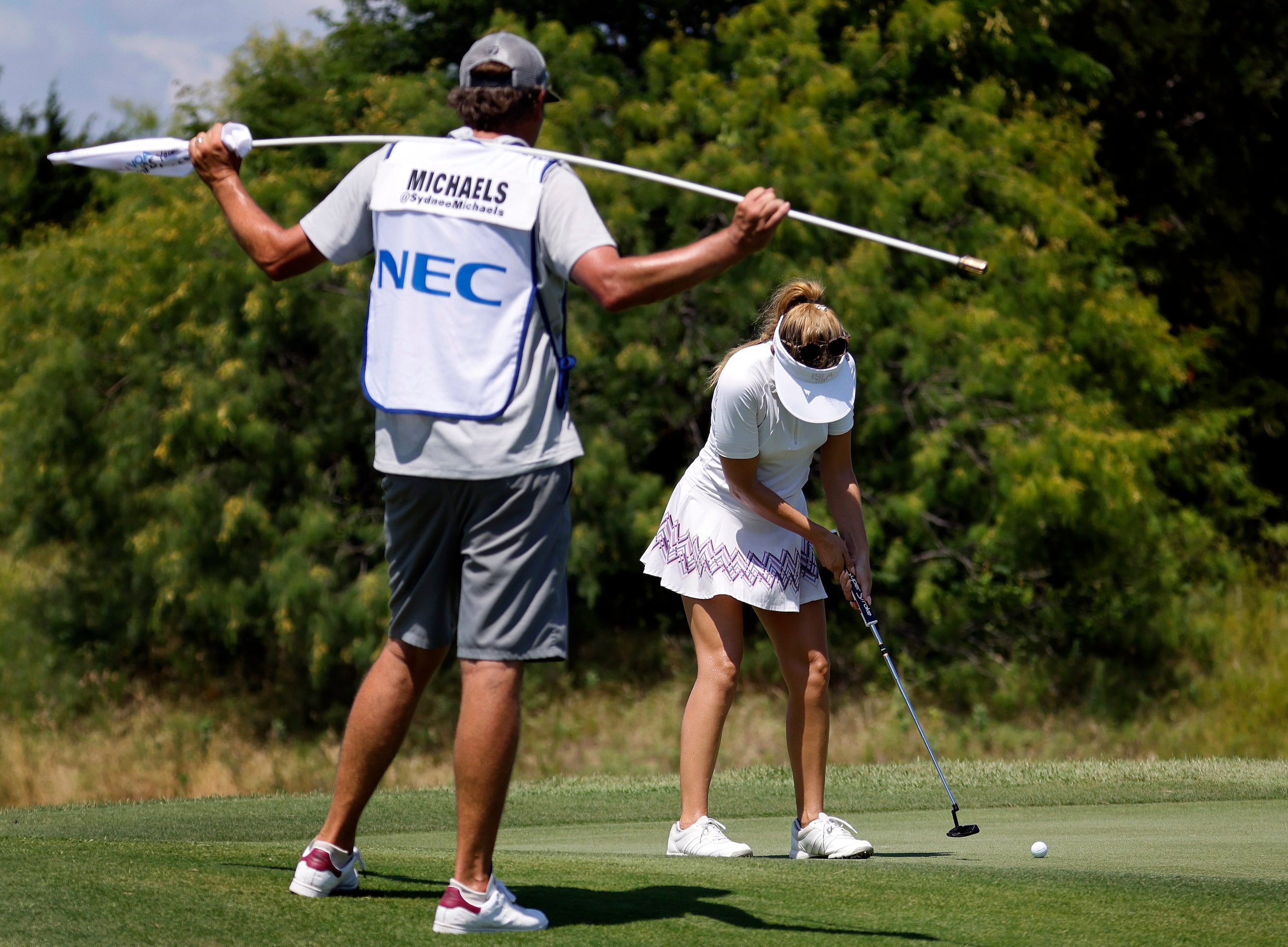 With her caddie looking on, professional golfer Sydnee Michaels putts on No. 17 during the...