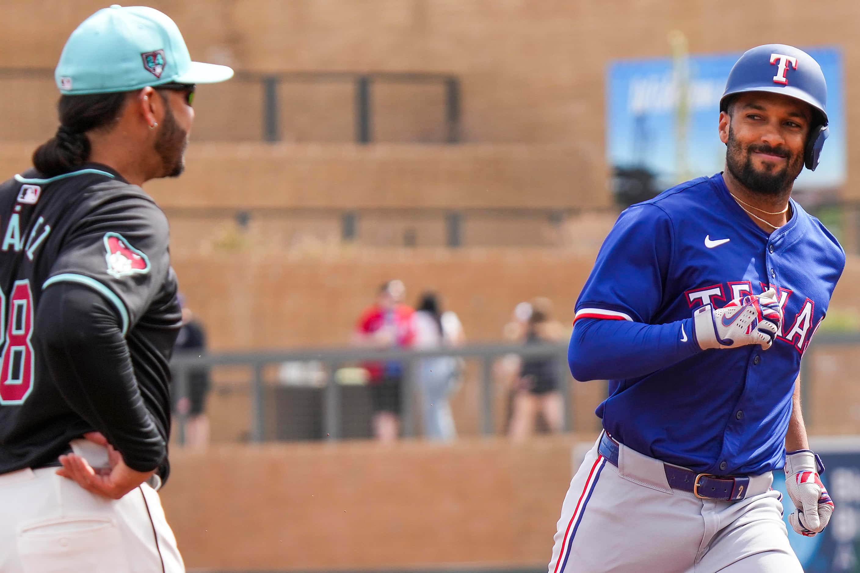 Texas Rangers infielder Marcus Semien smiles as he rounds the bases in front of Arizona...