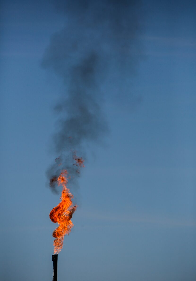 Black smoke streams from the flame of an oil storage tank flare stack in Texas' Permian...