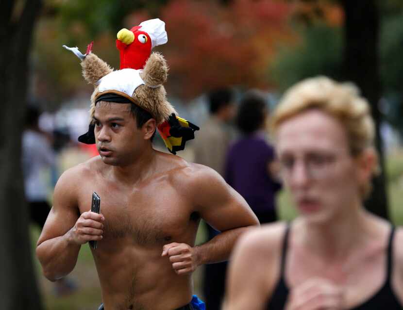 A man runs the 8-mile race wearing a turkey hat at the Dallas YMCA Turkey Trot in downtown...
