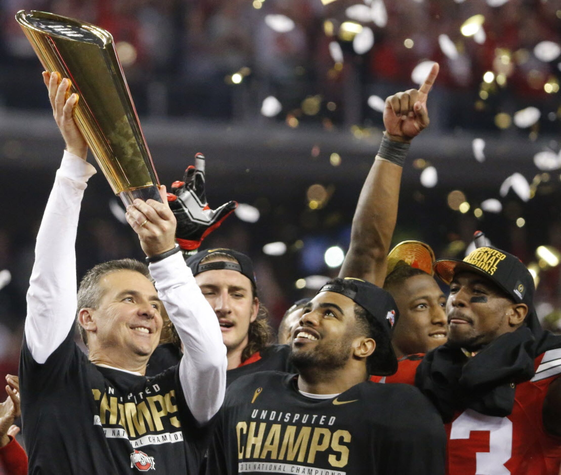 Ohio State head coach Urban Meyer hoists the national championship trophy as running back...