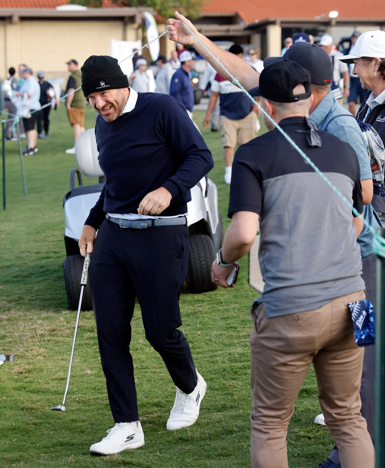 Fans help former Dallas Cowboys quarterback Tony Romo get under the ropes so he can make his...