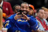 Drake toma una foto durante un juego de la NBA entre los Cleveland Cavaliers y los Houston...