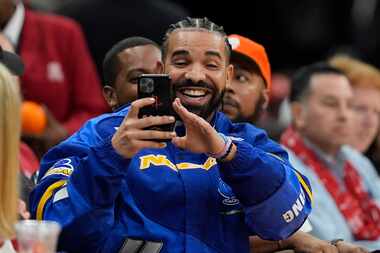 Drake takes a photo while attending an NBA basketball game between the Cleveland Cavaliers...