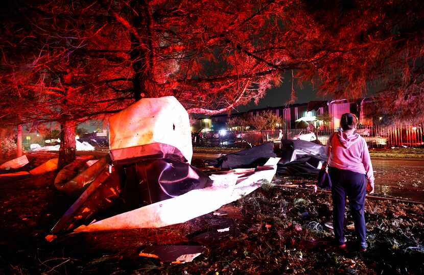 A person inspects the roofs from The Mirage Apartments that tore off and were wrapped around...