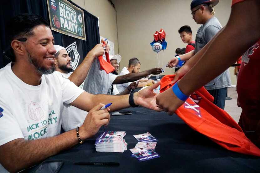 Texas Rangers pitcher Yovani Gallardo signs autographs for kids at the Back to School Block...