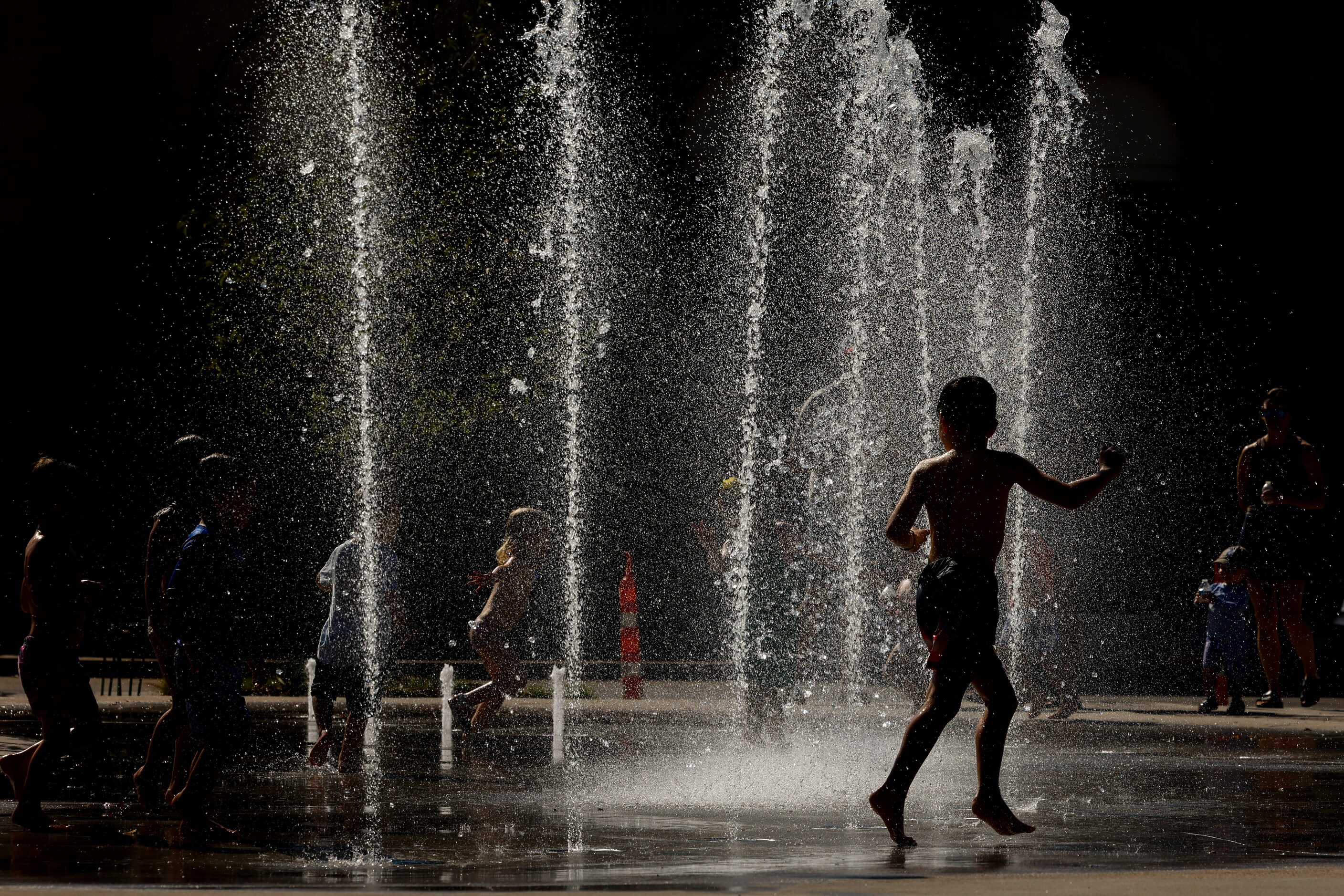 Kids play in the water fountain during the opening day of Harwood Park, on Saturday, Sept....