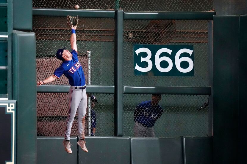 Texas Rangers left fielder Evan Carter (32) leaps and catches a deep ball by Houston Astros...