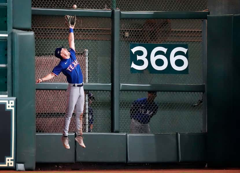 Texas Rangers left fielder Evan Carter (32) leaps and catches a deep ball by Houston Astros...