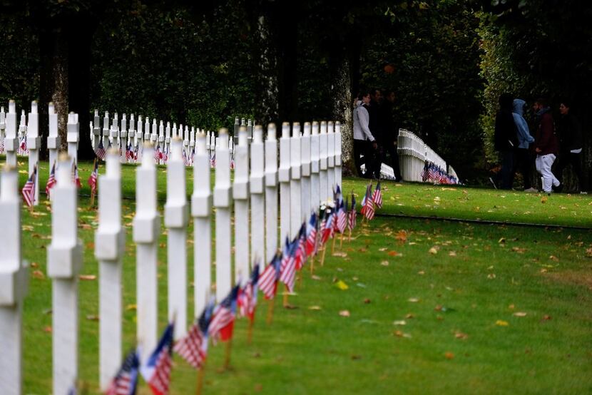 People walk past graves graves at the Meuse-Argonne American Cemetery and Memorial in...
