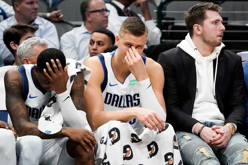 Injured Dallas Mavericks guard Luka Doncic (right) sits on the bench with forward Kristaps...