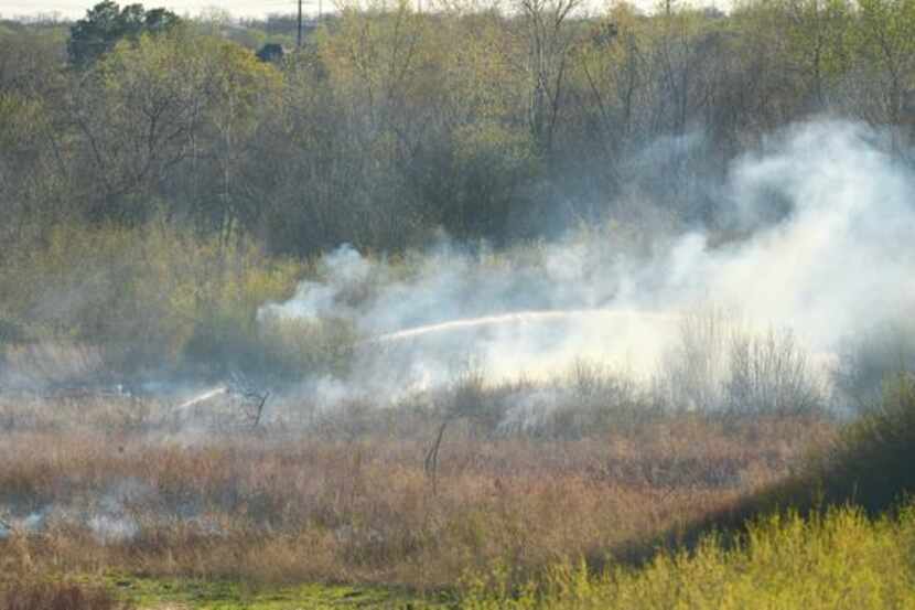 
A Lewisville Fire Department boat sprayed water along Hickory Creek to help control a brush...