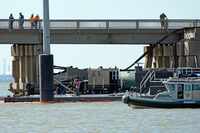 Workers survey the site where a barge crashed into the Pelican Island Bridge, Wednesday, May...