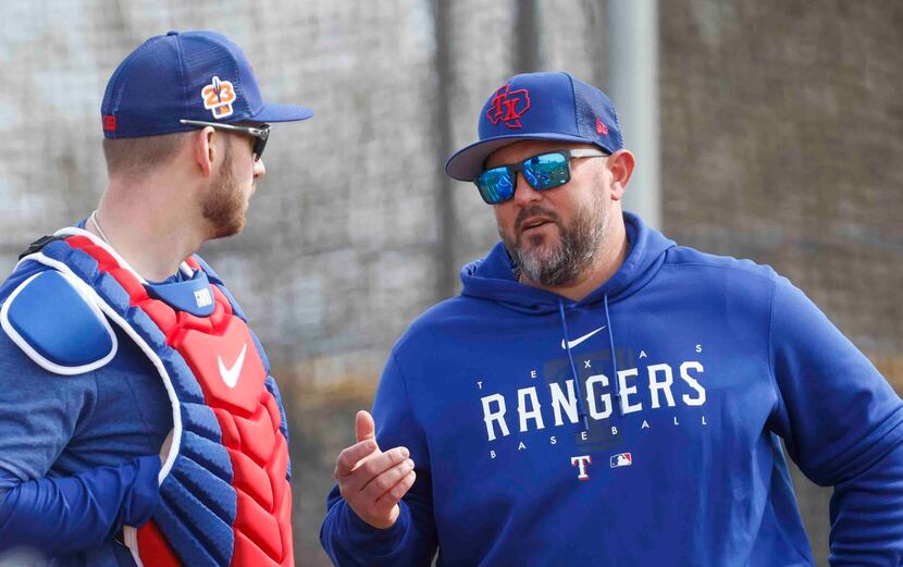 Texas Rangers catcher Mitch Garver, left, talks to catching coach Bobby Wilson during a...