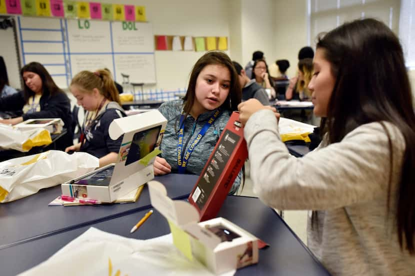 Students Dafne Sanchez, left, and Sandra Sanchez, look over their free tablets after...