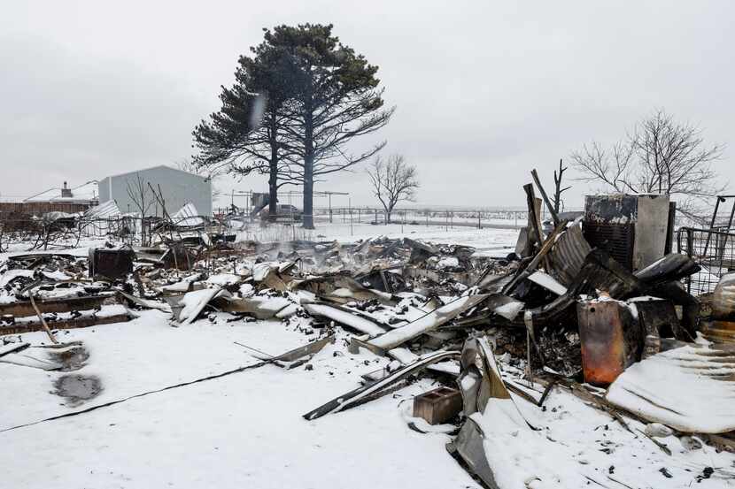 Snow falls over the charred remains of a home after being destroyed by the Smokehouse Creek...