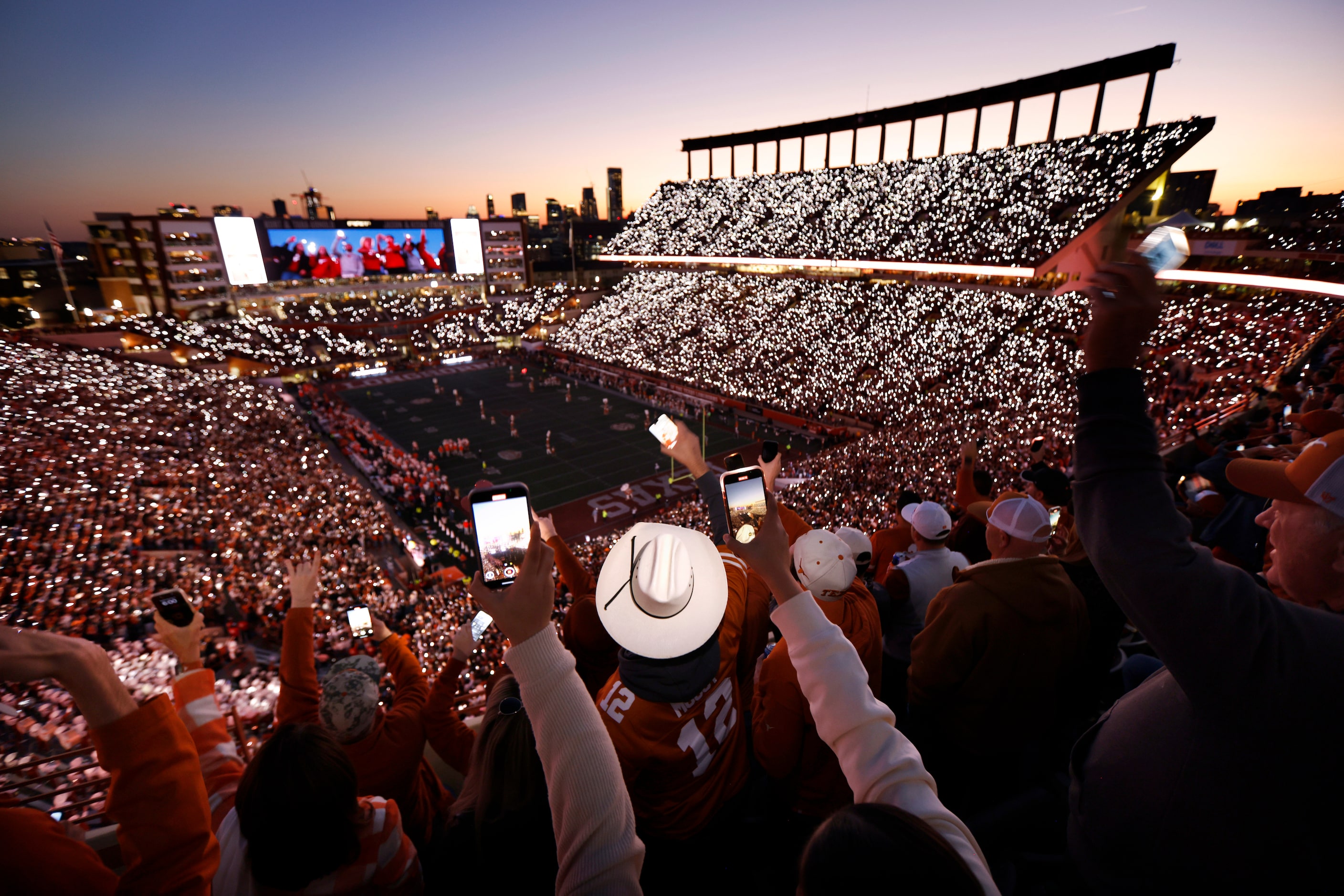 With the lights out, Texas Longhorns fans raises their phones as actor Matthew McConaughey...