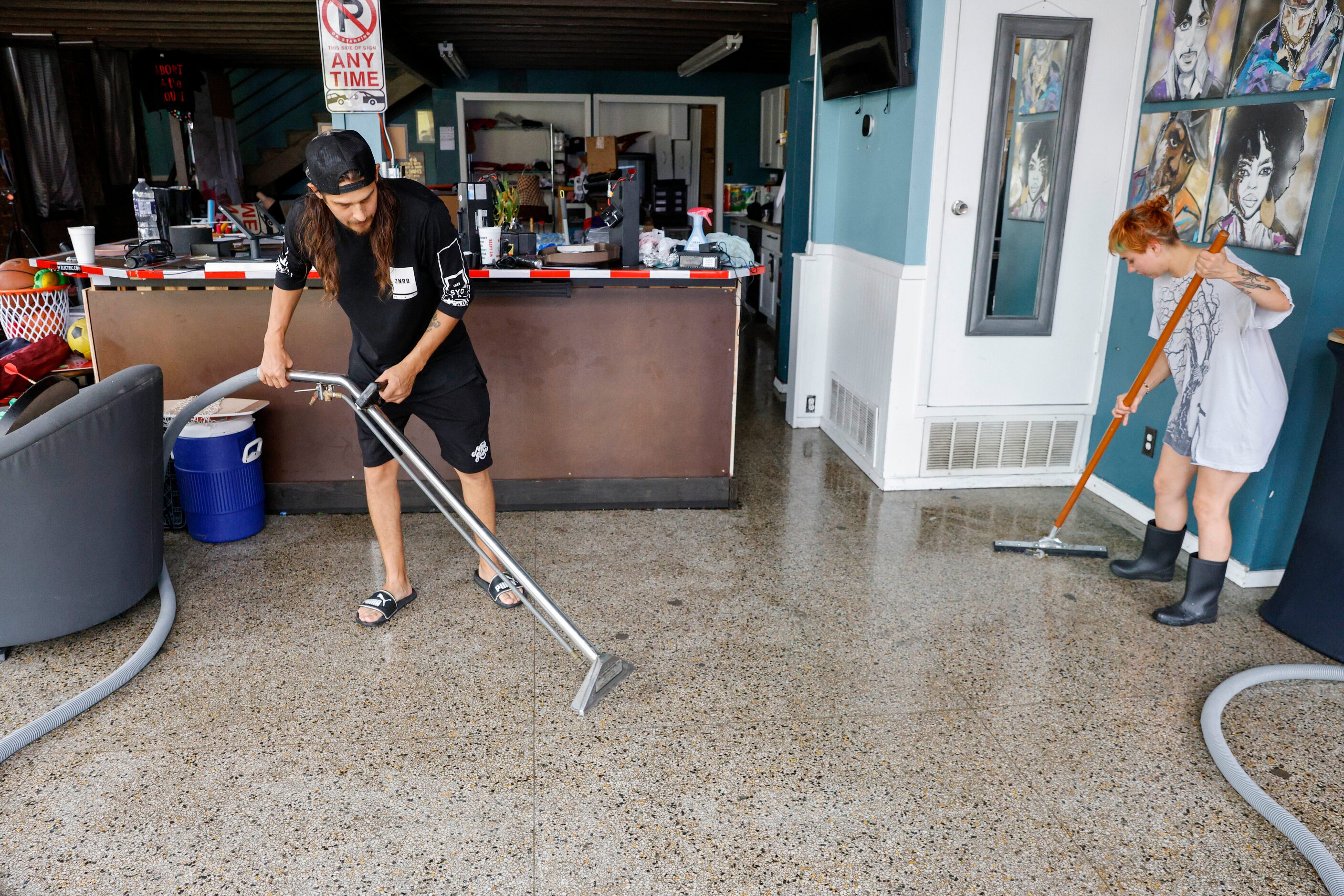 Airto Castañeda-Cudney, Ellum Electric owner (left), and Katheryn Jones clean up water after...