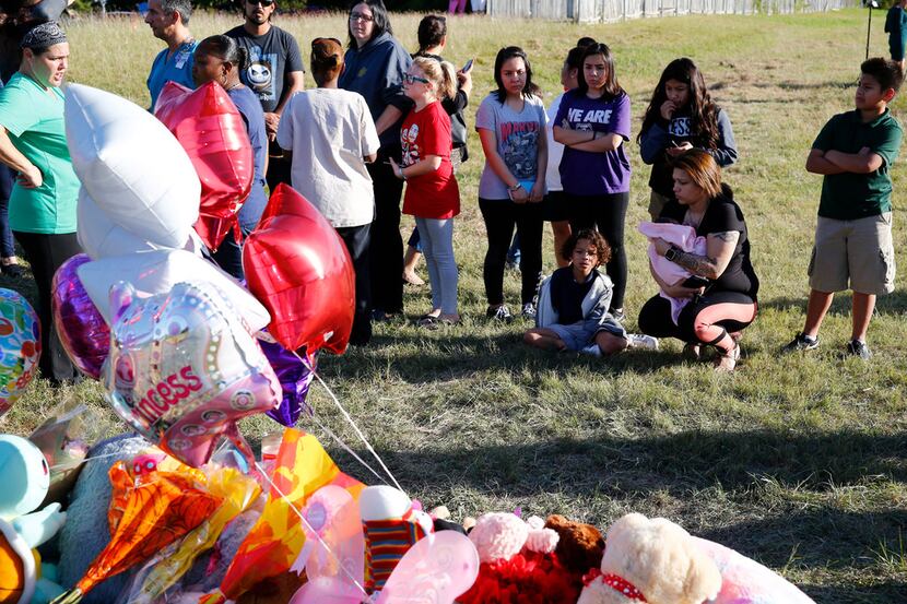 People gather near where the body of a small child was found Sunday morning during the...