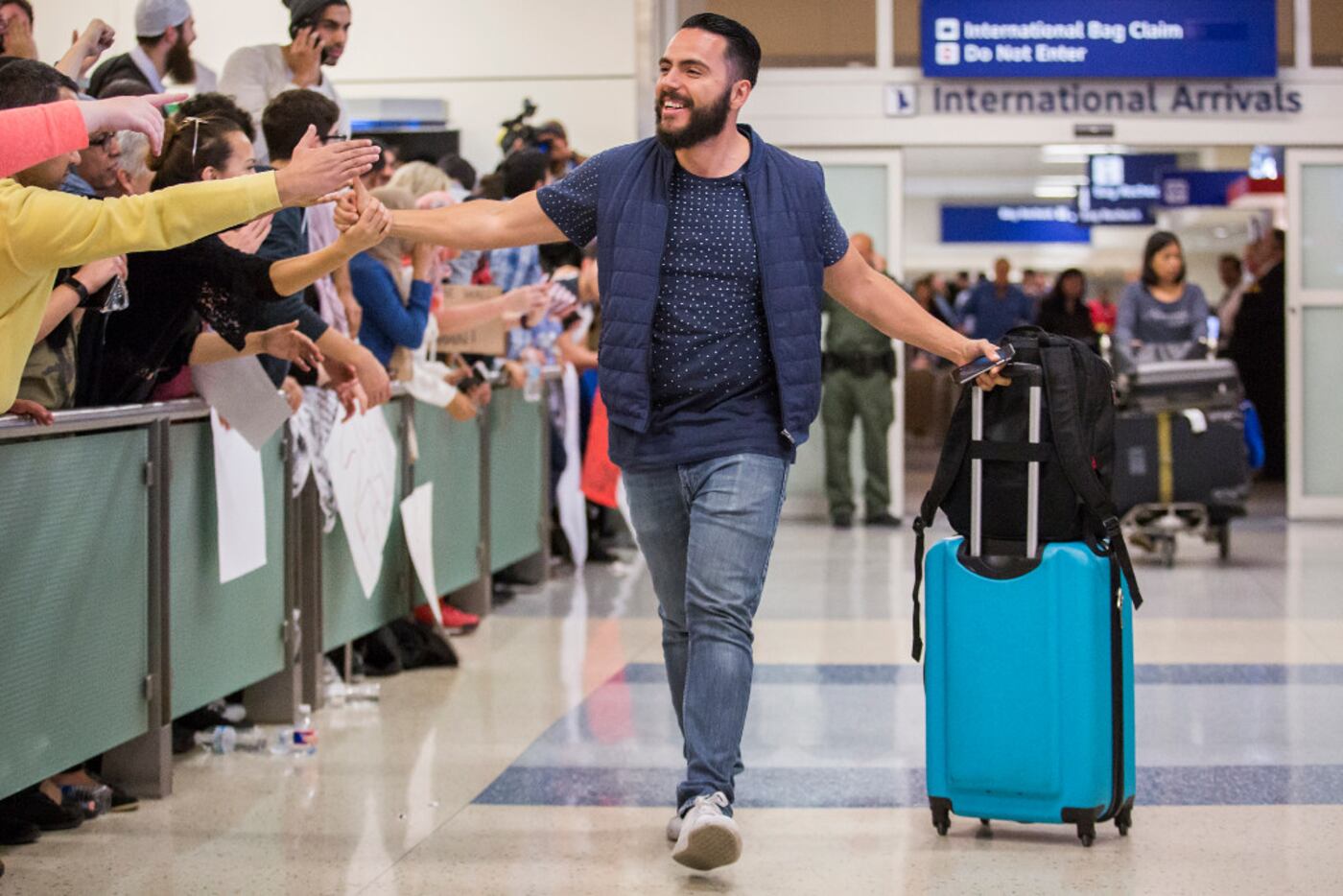 Traveler Alex Galindo high-fives protesters at DFW International Airport holds signs in...