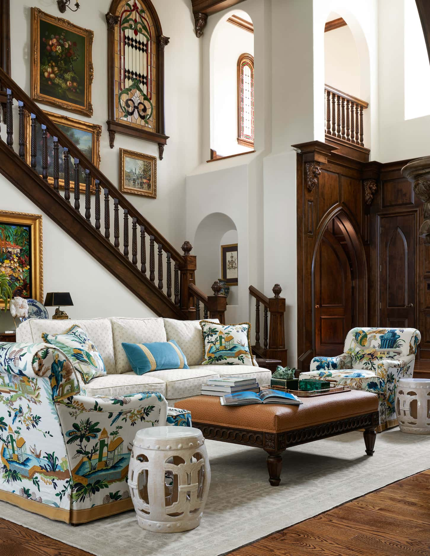 Armchairs in a patterned upholstery fabric flank either side of a cream-colored sofa in a...